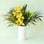 Narrow white cylinder vase filled with palms and tropical flowers not included with purchase. The vase lays against a light green background.
