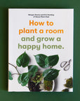 A white book with a green leafy plant and a title that reads, "How to plant a room and grow a happy home."