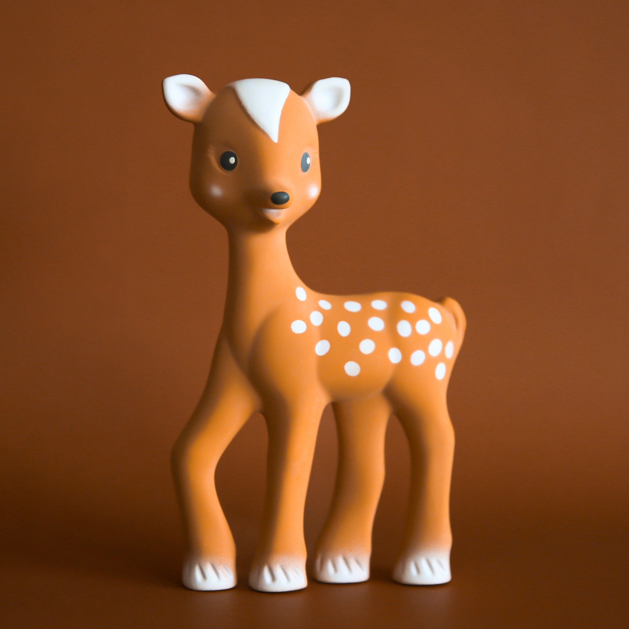 On a brown background is a fawn children's toy with cream accents.
