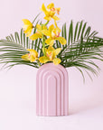 An arched ceramic vase in a cool toned pink shade.