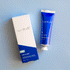 On a blue background is a blue bottle of hand cream with silver text that reads, "capri BLUE 06 Volcano".
