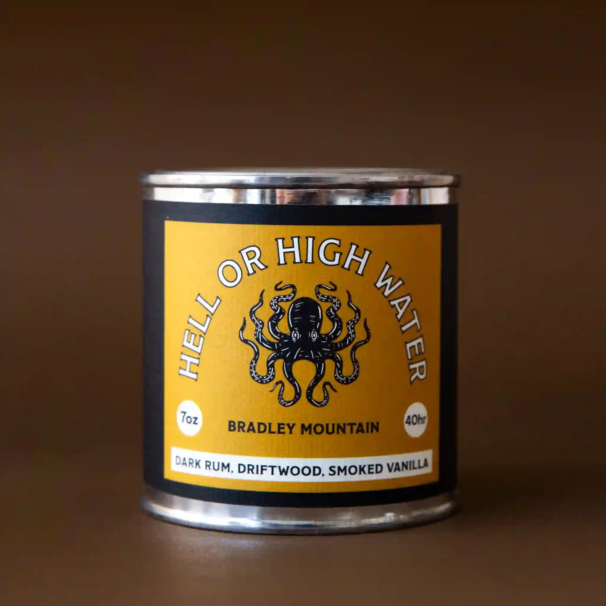 On a brown background is a tin candle with a yellow label featuring a octopus graphic and text arched above it that reads, &quot;Hell or High Water Bradley Mountain&quot;.