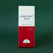 On a green background is a red and white package of chocolate with text that reads, "peppermint bark", "white chocolate peppermint candy chocolate chips".