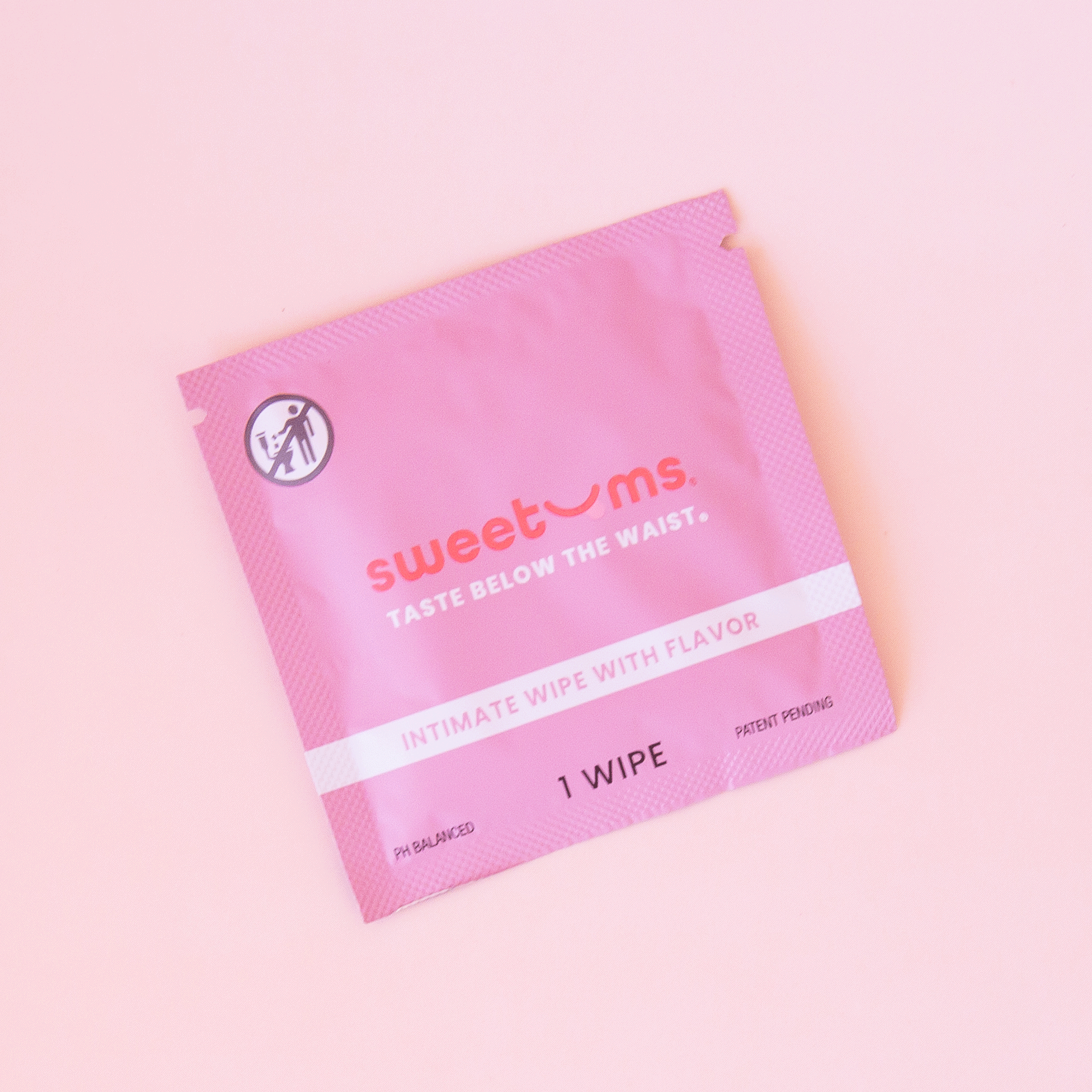 On a light pink background is a hot pink packet of a feminine wipes with text on the front that reads, &quot;sweetums taste below the waist intimate wipe with flavor&quot;.