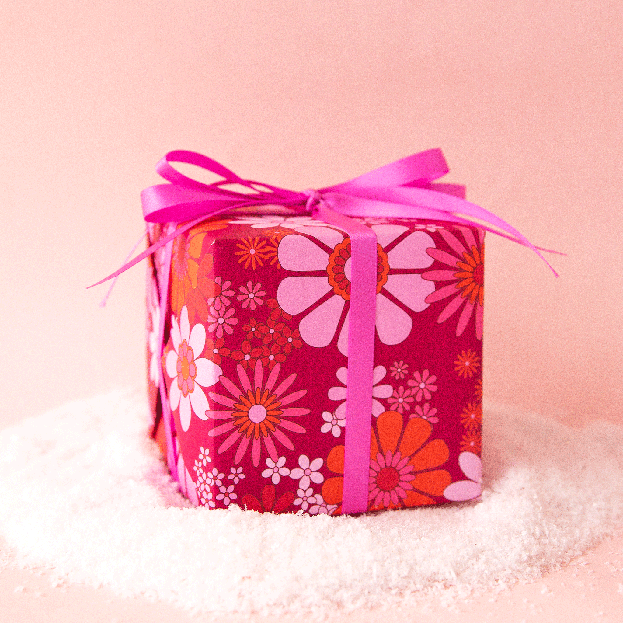 On a pink background is a hot pink and orange floral gift wrap. 