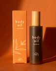 On an orange background is a bottle of body oil with a tan cap and an orange box packaging along with text on the front that reads, "body oil daydream".