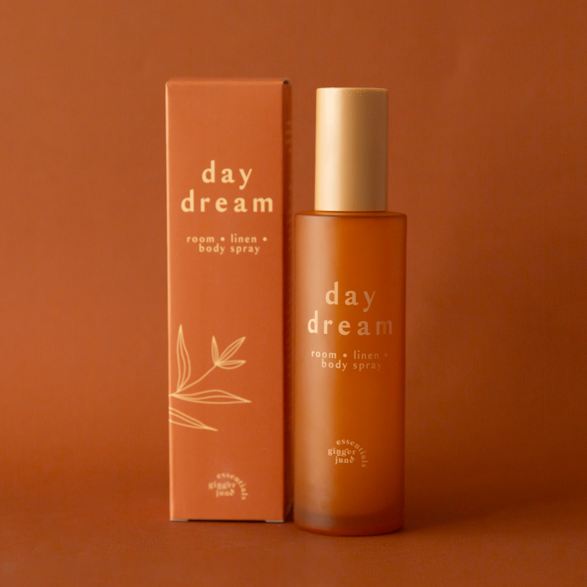 On a burnt orange background is an orange packaged spray with text that reads, &quot;day dream room linen body spray&quot;.