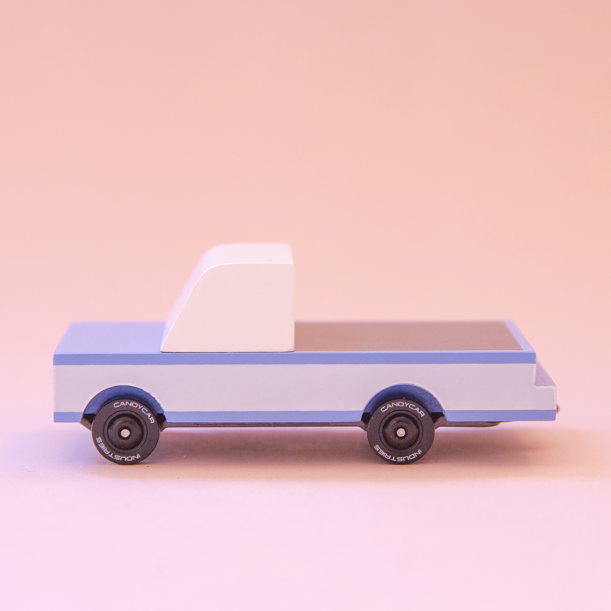A blue wooden toy pickup truck on a peachy background.