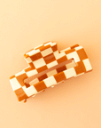 On a tan background is an ivory and orange rectangle claw clip.
