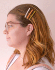 Three acetate bobby pins from top to bottom is an ivory shell shade, mango orange, and olive green shade.