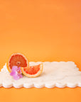 A white marble rectangle cutting board with a scalloped edge.