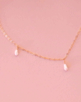 A dainty gold chain necklace with five freshwater pearls hanging spaced out on the chain.