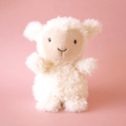 On a pink background is a white and tan lamb shaped stuffed animal. 