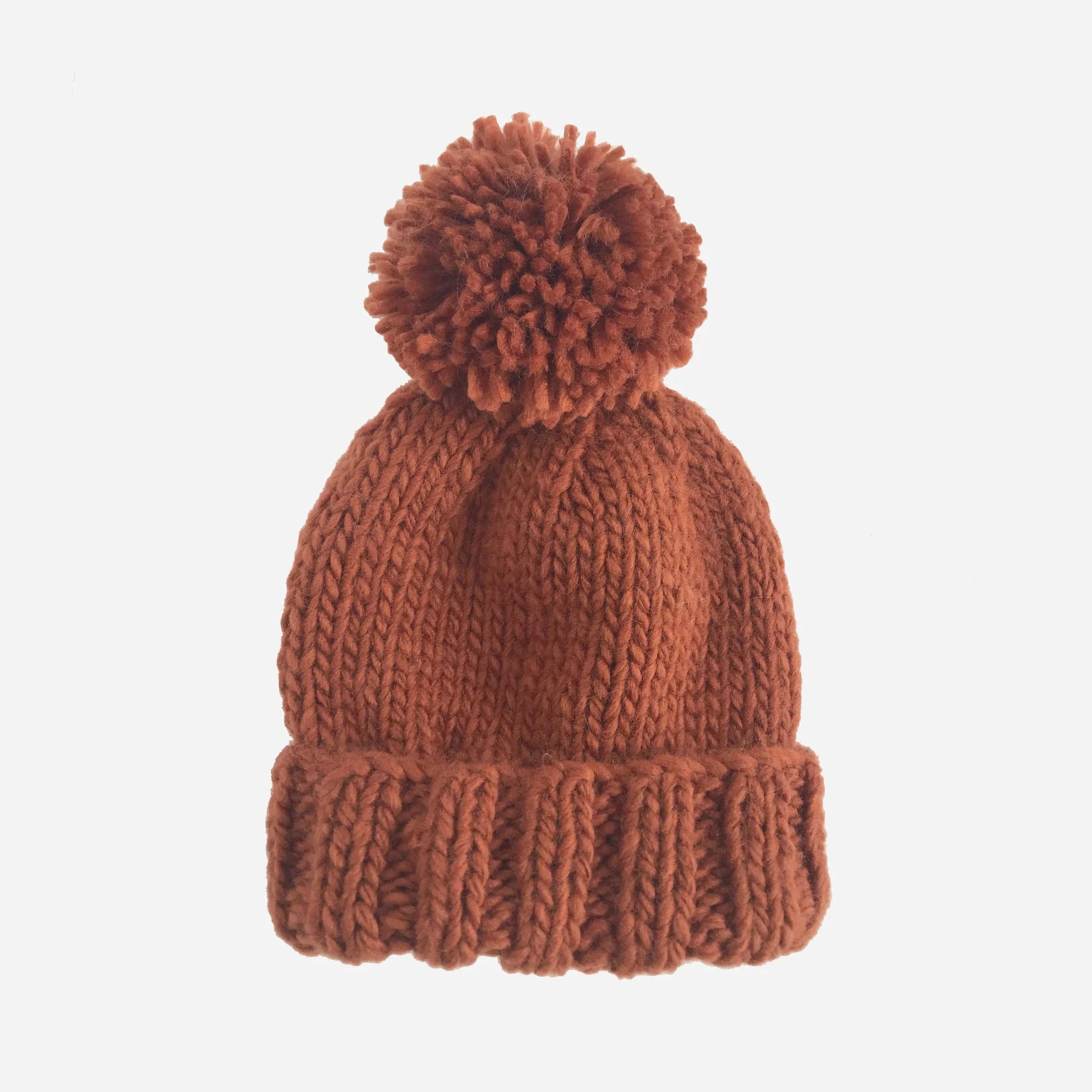 A reddish colored knit beanie with a pom pom on top.