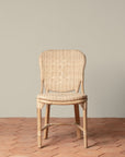On an ivory background is a rattan chair with a woven rattan seat and backrest.