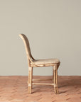 On an ivory background is a rattan chair with a woven rattan seat and backrest.