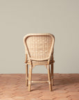 On an ivory background is a rattan chair with a woven rattan seat and backrest.