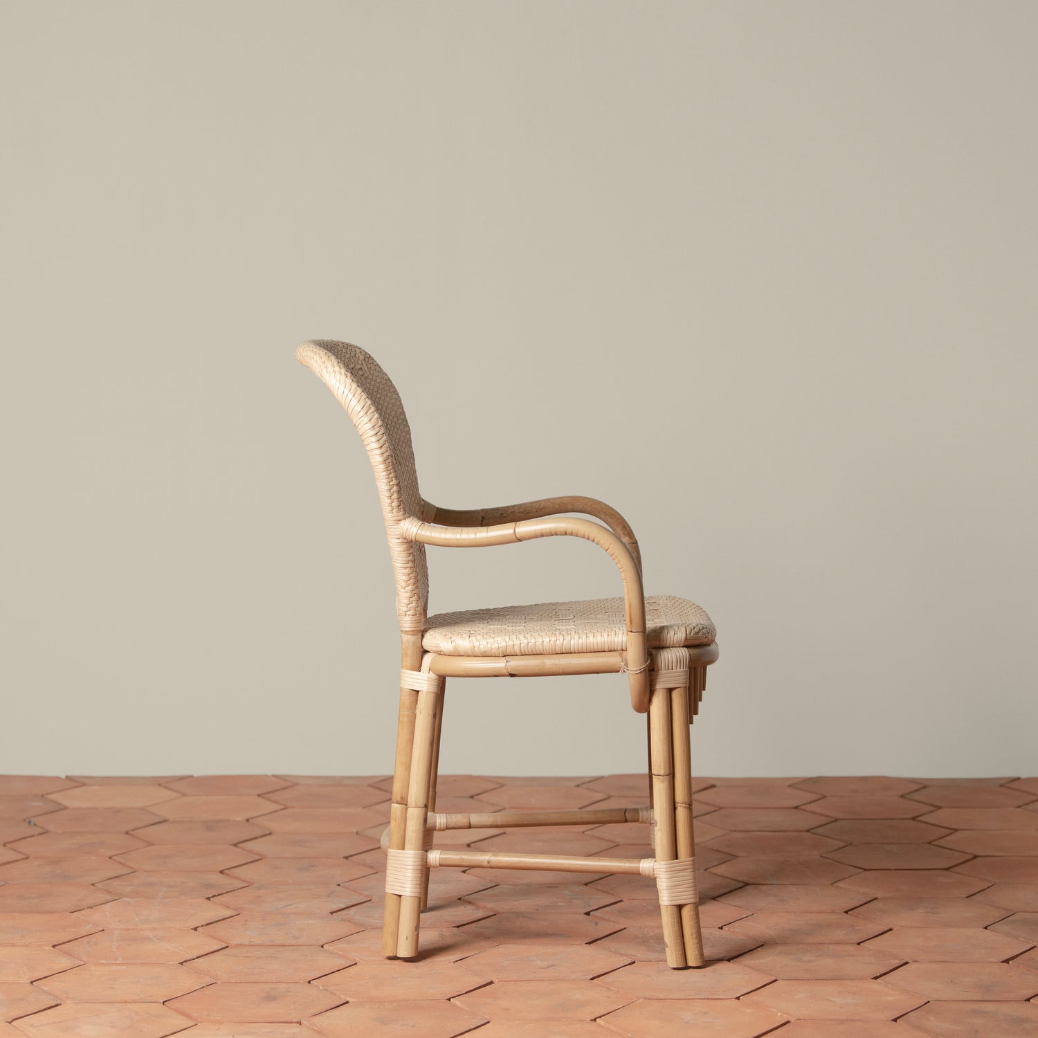 On an ivory background is a rattan chair with a woven rattan seat and backrest.