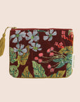 A maroon, green, and light blue velvet pouch with a chartreuse tassel zipper.