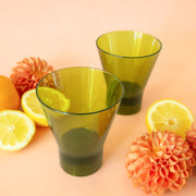 A set of four glass, olive green tumblers in a pink and orange striped box.