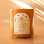 An orange candle with an arched label with a lion graphic and text above that reads, 'Golden Sunset'.