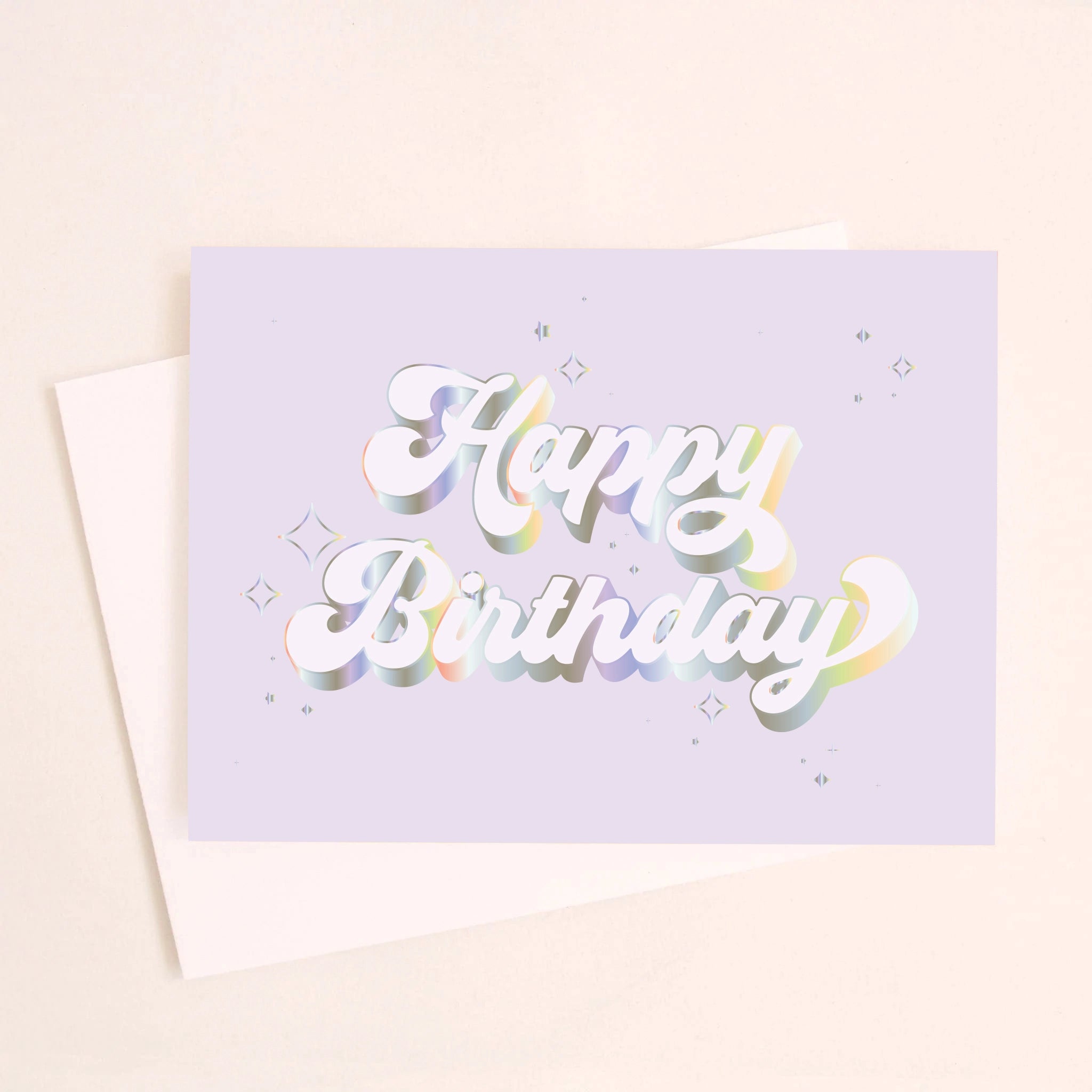 On an ivory background is a light purple/blue greeting card with white / holographic outlined text that reads, &quot;Happy Birthday&quot; along with a white envelope.