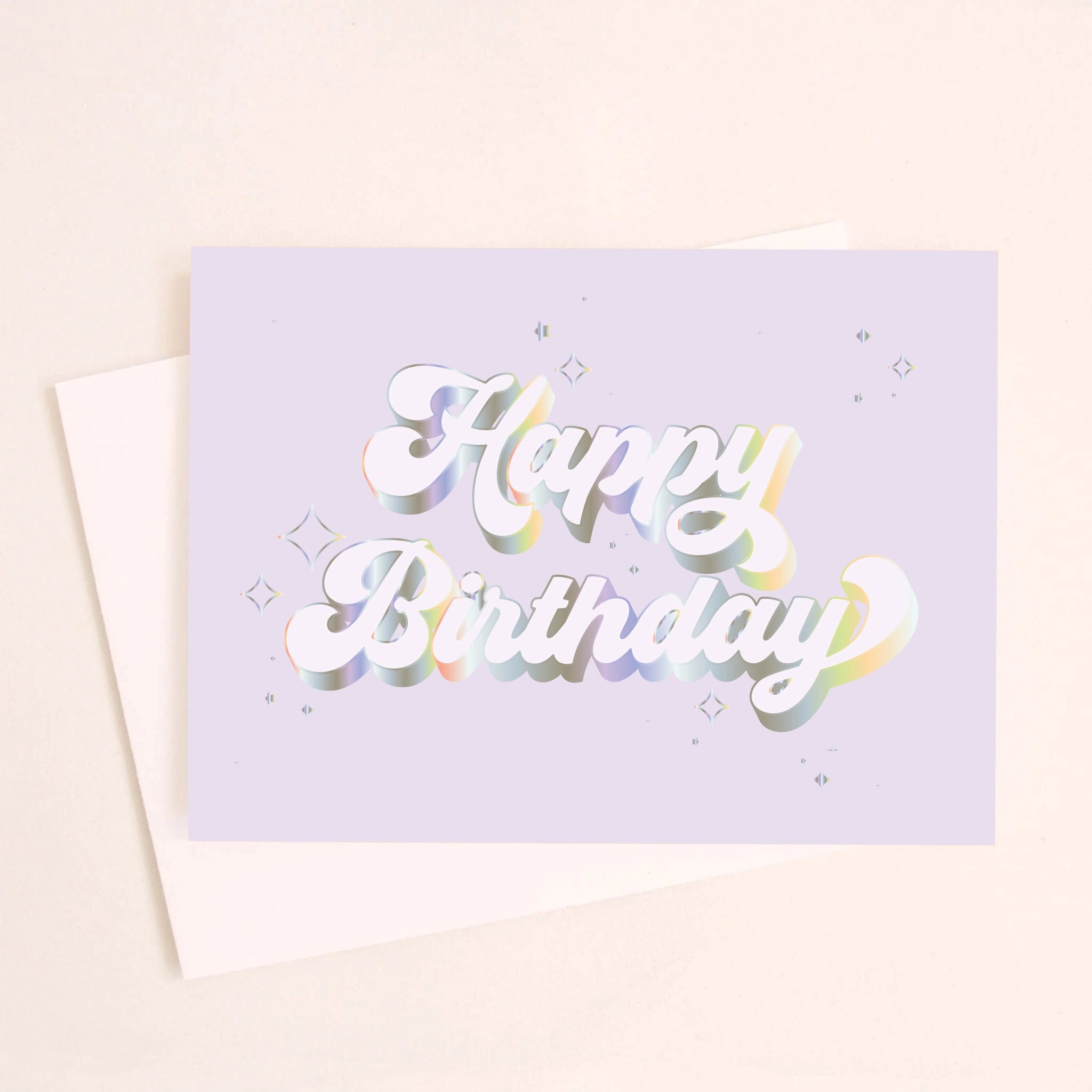 On an ivory background is a light purple/blue greeting card with white / holographic outlined text that reads, "Happy Birthday" along with a white envelope.