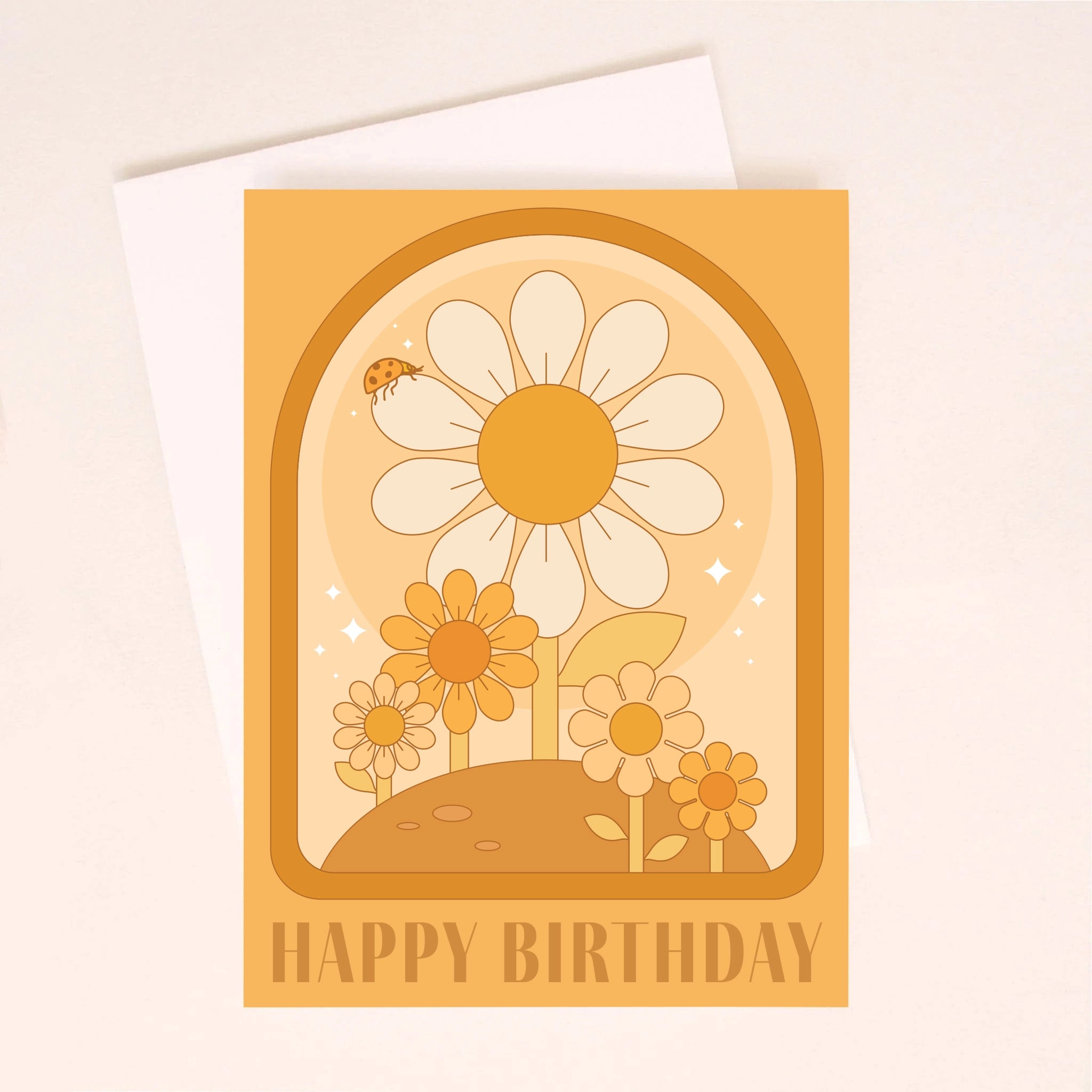 On an ivory background is an orange greeting card with a darker orange arched border and daisy illustrations inside along with text at the bottom that reads, &quot;Happy Birthday&quot;. Also included is a white envelope.