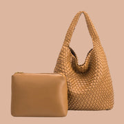 A camel tan colored woven handbag with a zipper pouch insert.