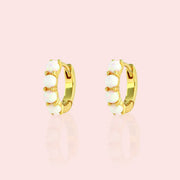 A gold plated pair of white opal huggie hoop earrings.