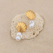 A pair of gold shell earrings with pearl beads underneath them.