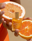 A bottle of orange aromatherapy essence with a gold lid that reads, 'Leahlani Pamplemouse Aromatherapy Essence'.
