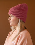 A knit beanie in a berry pink color.