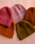 An assortment of five knit beanies in five different colors.