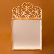 A rattan mirror with daisy rattan design on the top edge.