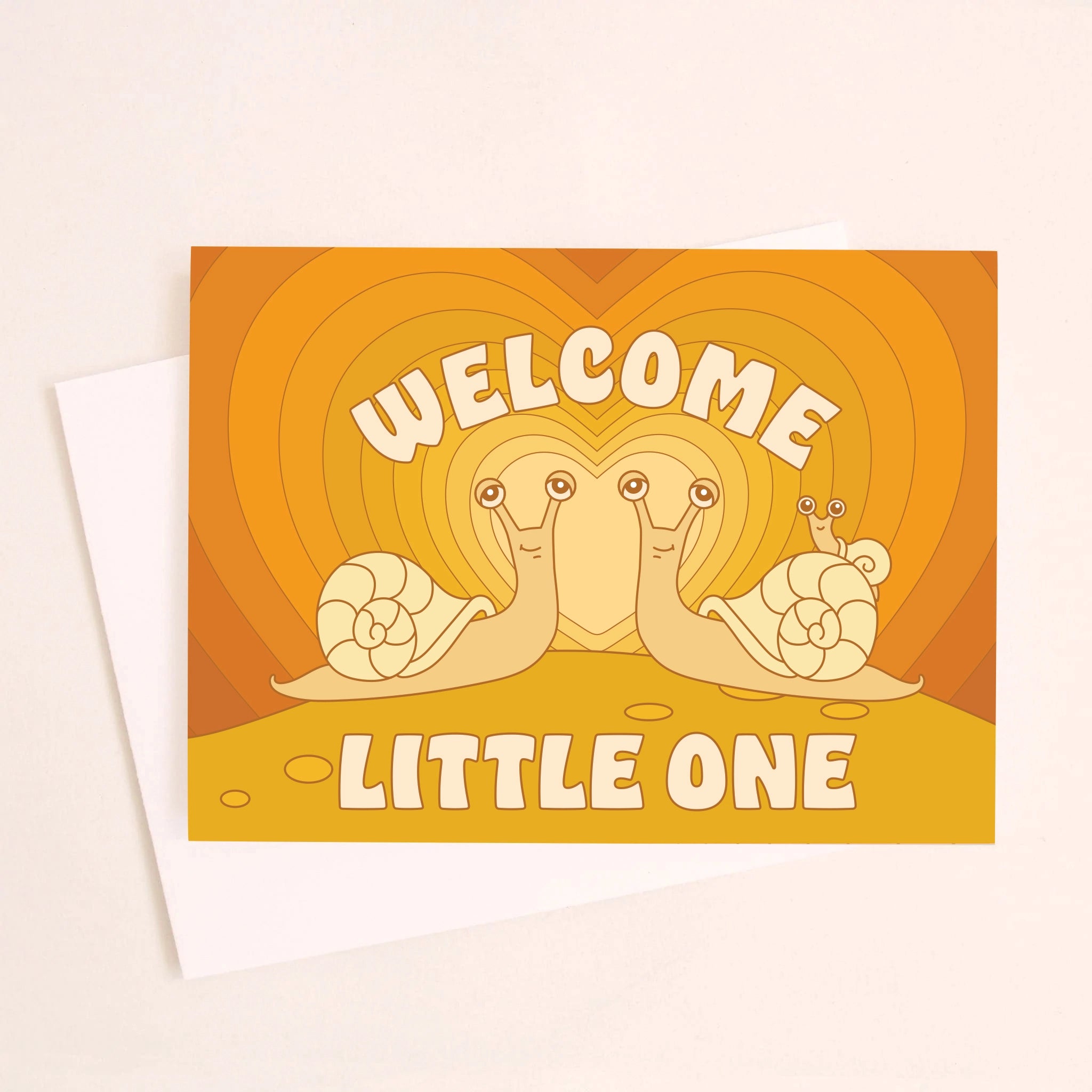 On an ivory background is an orange greeting card with an orange gradient heart background and two snails facing one another with a baby snail on the back of one along with text above and below that reads, &quot;Welcome Little One&quot;.