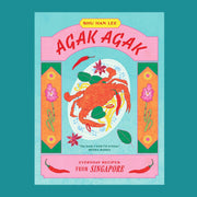 A multi colored cook book with an illustration of a crab dish on a plate and red text that reads, 'Agak Agak Everyday Recipes From Singapore'.