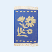 A blue hand towel with a cream floral print design and fringe details on each end.