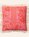A pink and orange tropical print pillow with a. tassel edge.