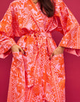 A cotton robe with pockets and an orange and hot pink tropical floral print.
