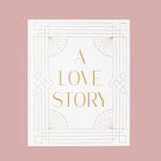 On a pink background is an ivory photo album cover with gold text that reads, "A Love Story".