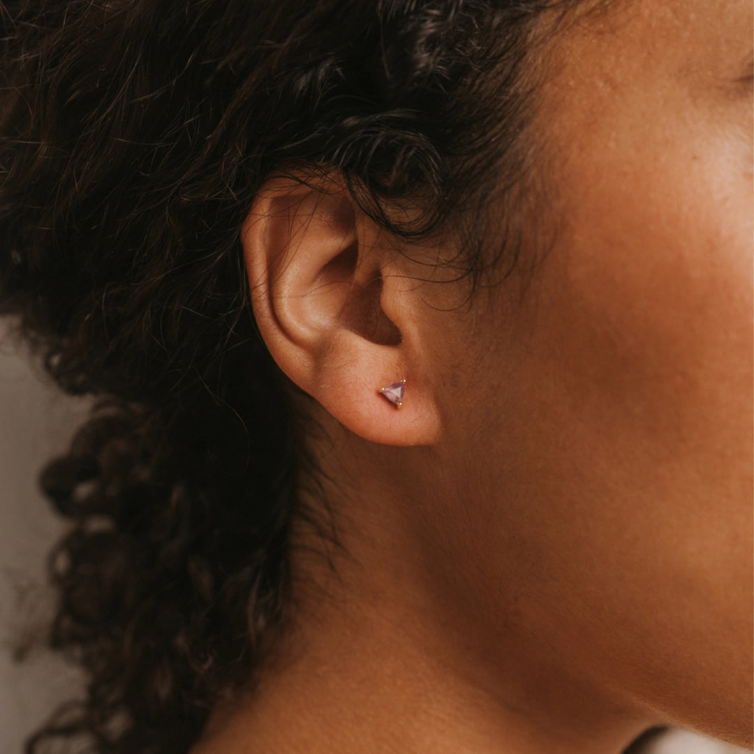 Triangle shaped amethyst set gem on gold stud earrings.