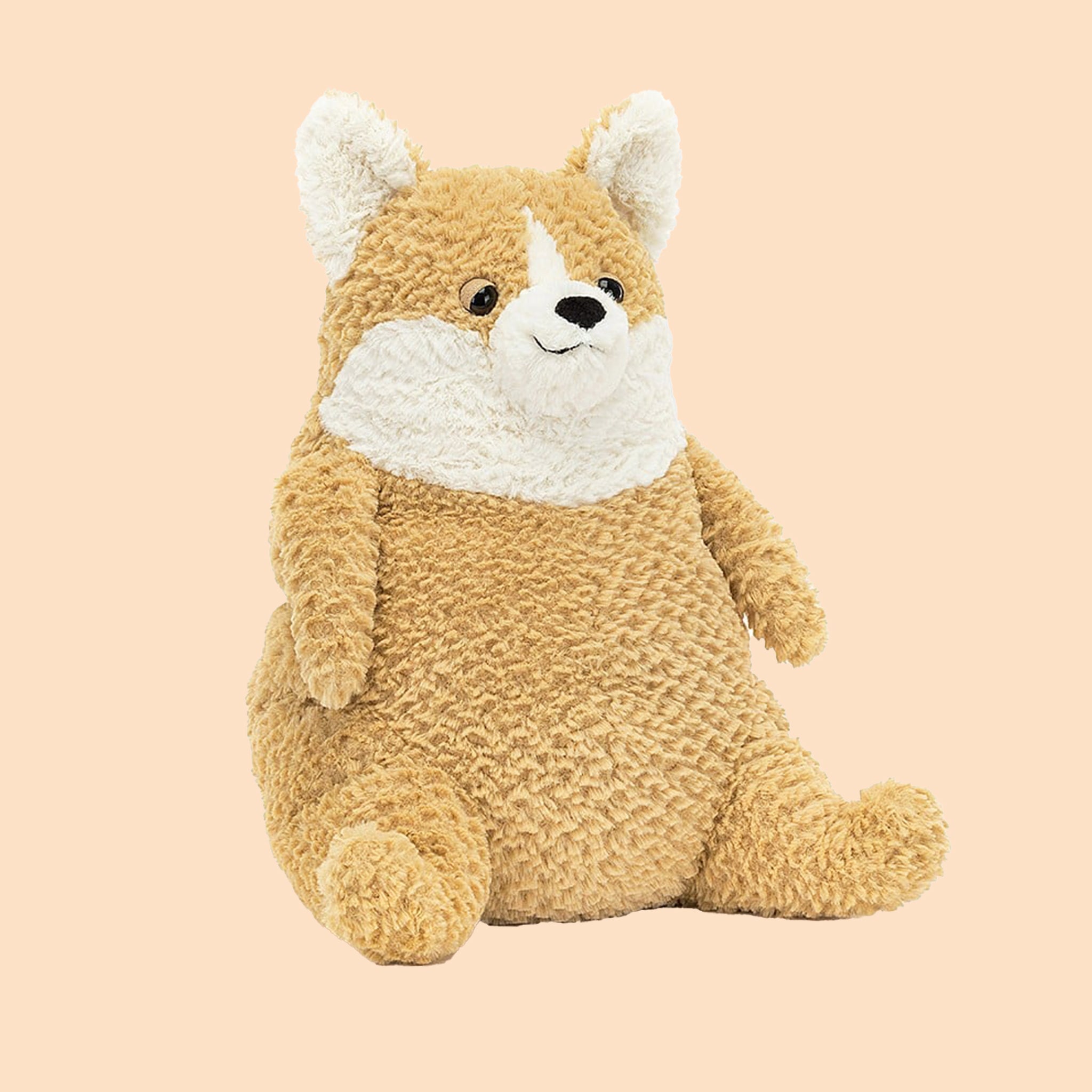 On a tan background is a tan and white corgi shaped stuffed animal toy. 
