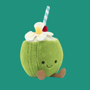 A coconut shaped stuffed toy with a tropical flower, smiling face and straw.