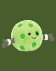 A round pickleball shaped stuffed toy with a smiling face and two arms and hands.