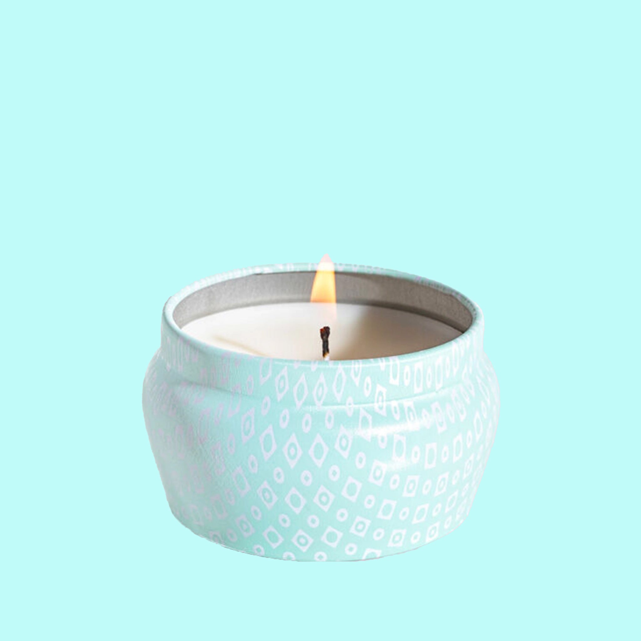 A small blue tin candle with white wax and a white diamond repeating pattern on the outside of the tin. Comes with a matching blue lid that reads, &quot;Capri Blue Volcano&quot;.