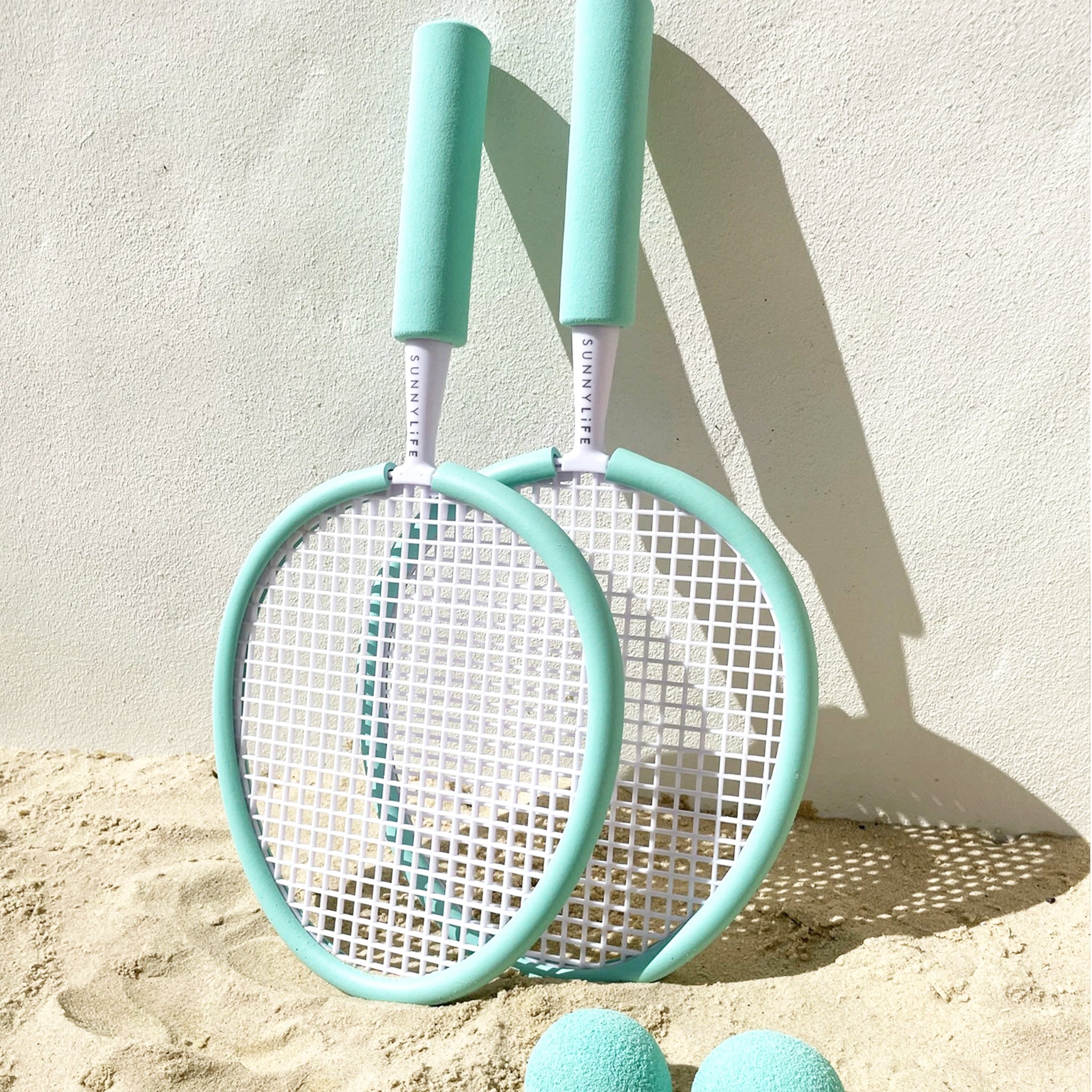 A pair of aqua rackets with two balls.