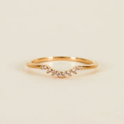 On a tan background is a gold ring with small cubic zirconias along the small dip.