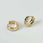 A pair of gold hoop earrings with star etching.