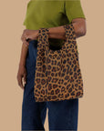 A small nylon tote bag in a leopard print that folds up into a small pouch.